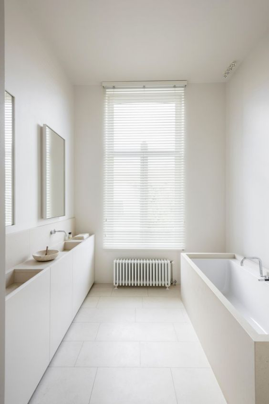 Badezimmer ganz in Weiß Minimalismus herrscht schmaler Raum sehr elegant gestaltet Fenster Spiegel Waschtisch