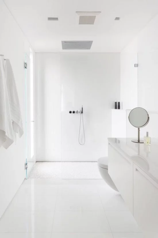 Badezimmer ganz in Weiß Minimalismus pur weiße Tücher kleiner runder Spiegel
