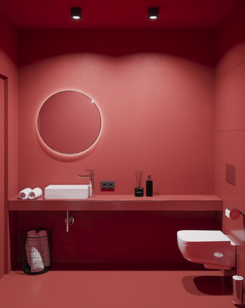 Badezimmer in Rot WC weiß Waschtisch Waschbecken weiß Handtücher alles andere rot coole Beleuchtung runder Spiegel