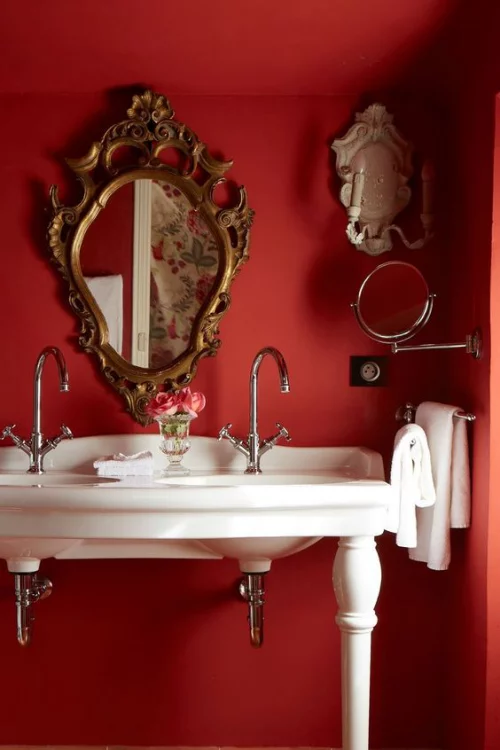 Badezimmer in Rot rote Wand weißer Waschtisch Retro Wandspiegel verzierter Rahmen weiße Handtücher
