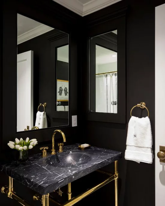 Badezimmer in Schwarz und Gold Waschtisch schwarzer Marmor natürliches Licht zwei Spiegel weiße Tulpen weißes Tuch