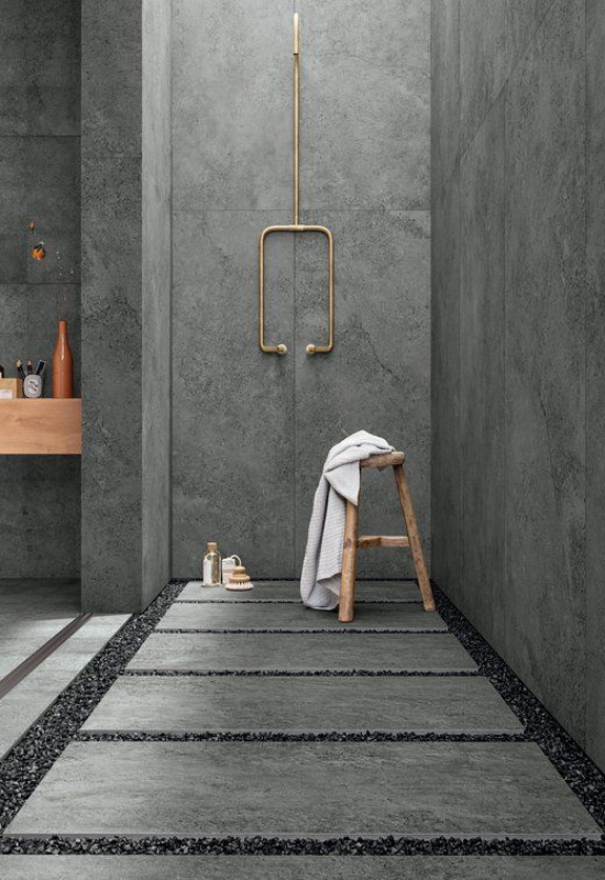 Baddesigns in Grau Industrial Style Betonwände Boden Streifen mit kleinen Steinen Dusche aus Messing