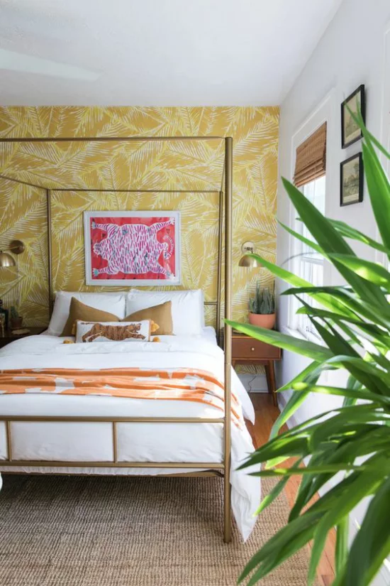 Glamouröse Schlafzimmer Himmelbett aus Metall Wand hinter dem Bett mit gelber Tapete grüne Zimmerpflanze rechts vorne