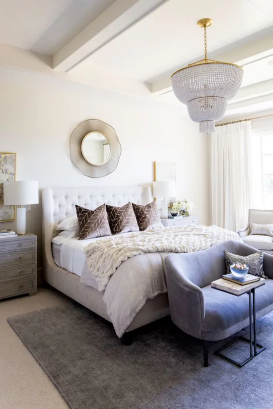 Glamouröse Schlafzimmer großes Bett runder Spiegel an der Wand Kronleuchter beigefarbene Kissen weiche Texturen