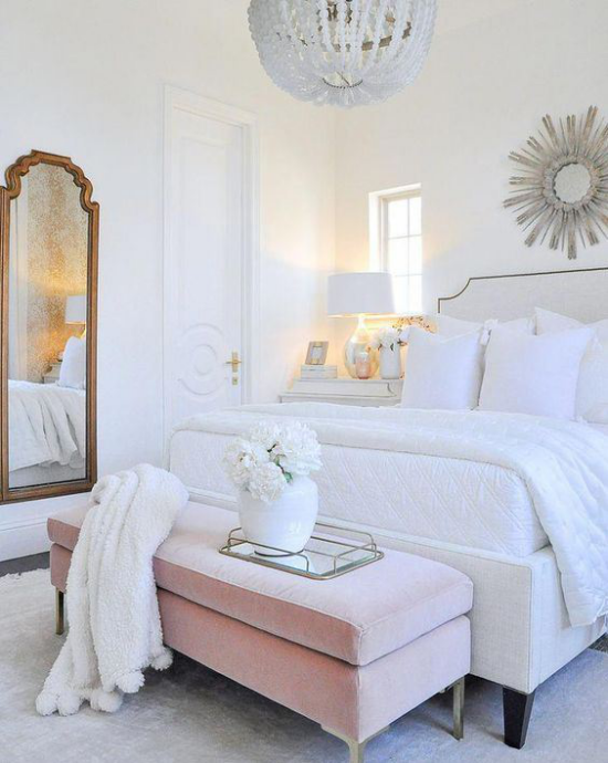 Glamouröse Schlafzimmer großes bequemes Schlafbett weiße Bettwäsche rosa Sitzbank weiße Vase mit Blumen Spiegel weiße Wurfdecken