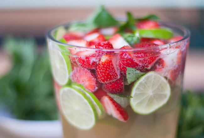 Sommerbowle zubereiten Erfrischungsgetränk an heißen Tagen ein Glas mit Erdbeeren Zitronenscheiben Minze