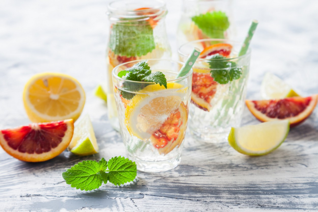 Sommerbowle zubereiten frisch lecker Zitrone in Scheiben geschnitten Minze Blätter im Glas