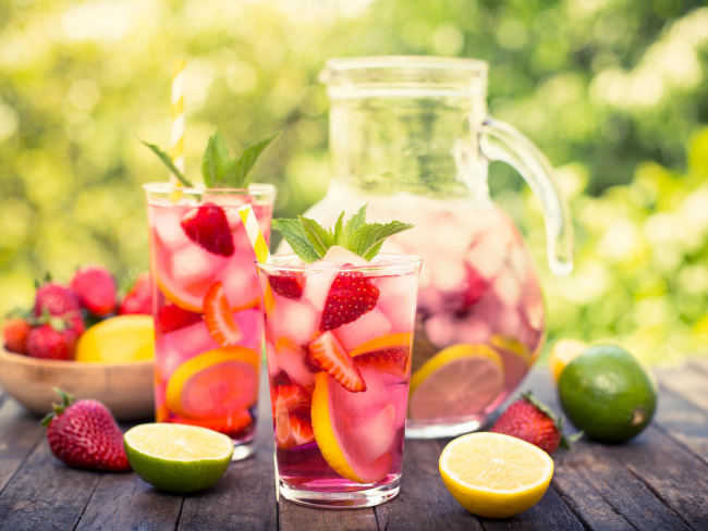 Sommerbowle zubereiten frisch lecker fruchtig Erdbeeren Zitronenscheiben große Glaskanne in Gläsern serviert