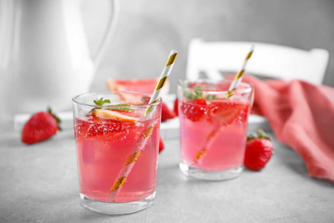 Sommerbowle zubereiten frisch lecker fruchtig Erdbeeren Zitronenscheiben zwei Gläser Strohhalme