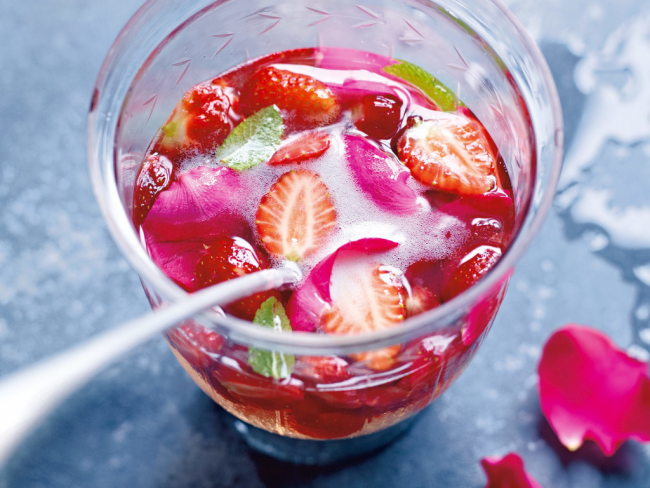 Sommerbowle zubereiten frisch lecker fruchtig im Glas serviert mit essbaren Blüten garniert