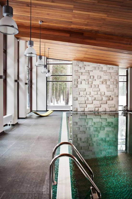 Hallenbad zu Hause interessantes Design Holzdecke gefliester Boden Ziegelwand Hängeleuchten hohe Glasfenster