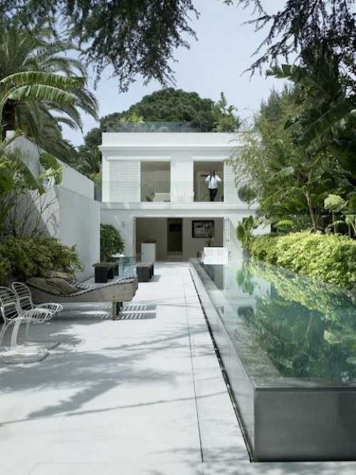Schmale Pools auf wenig Platz für kleine Gärten Glaswände weißes Haus Betonfläche Liege Stühle viel Grün