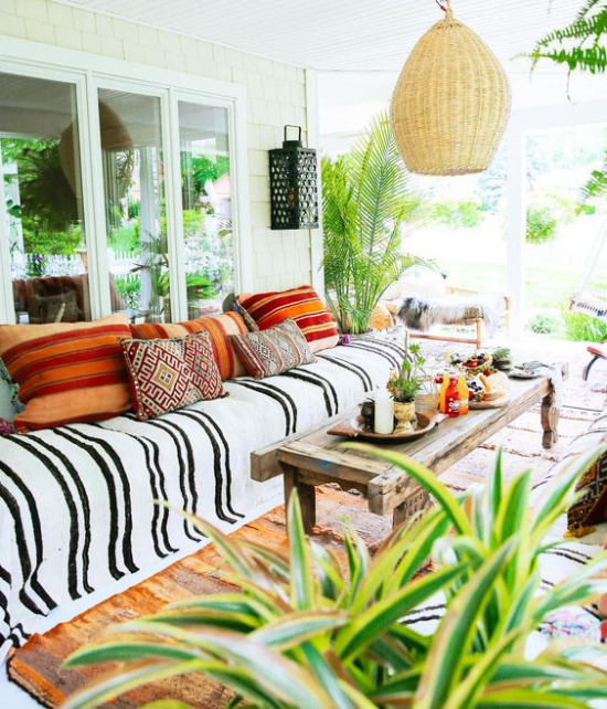 Boho Style Veranda Hängelampe aus Rattan viel üppiges Grün Deko Kissen Ethno-Muster langes Sofa