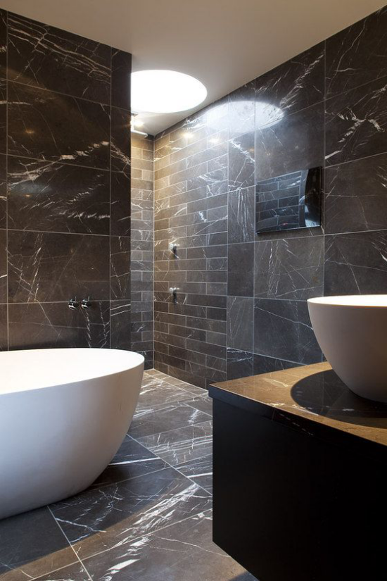 Schwarzer Marmor im Interieur schickes Badezimmer weiße Badewanne graue Marmorplatten