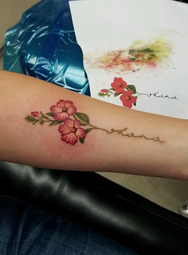 Unterarm-Tattoo mit Ohana-Schriftzug und Hibiskusblüten 