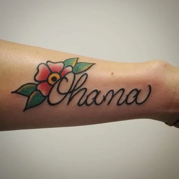 Ohana-Tätowierung mit Schriftzug und bunter Hibiskus-Blüte 