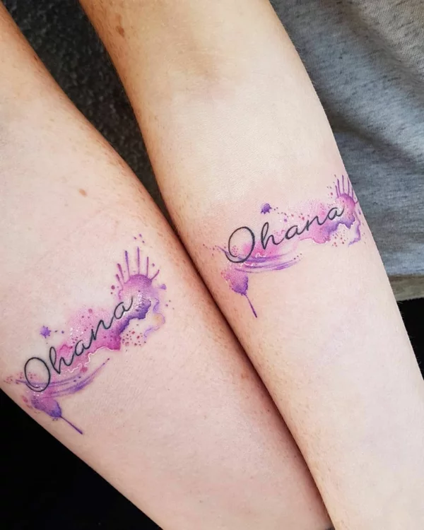 Ohana-Schriftzug Tattoos in lila Wasserfarben am Unterarm 