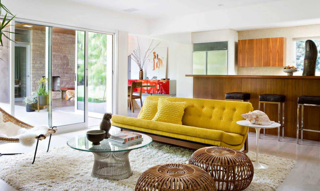 Mid-Century Modern Wohnstil Wohnzimmer große Glaswand gelbes Sofa Glastisch weißer Teppich Korbsessel