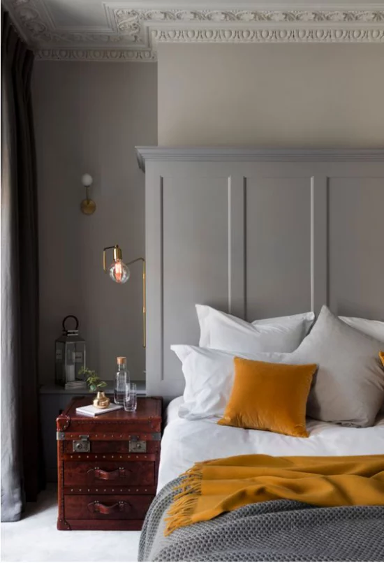 Schlafzimmer Ideen in Grau und Gelb einfache Raumeinrichtung alte Koffer als Nachttisch weiße Bettwäsche graue Decke gelbes Kissen