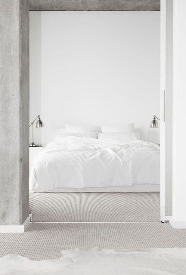Schlafzimmer minimalistisch einrichten weiße Bettwäsche Betonwand im Vordergrund Türrahmen