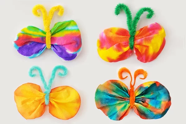 bunte Schmetterlinge basteln mit Kaffeefiltern in verschiedenen Farben und mit Pfeifenreinigern 