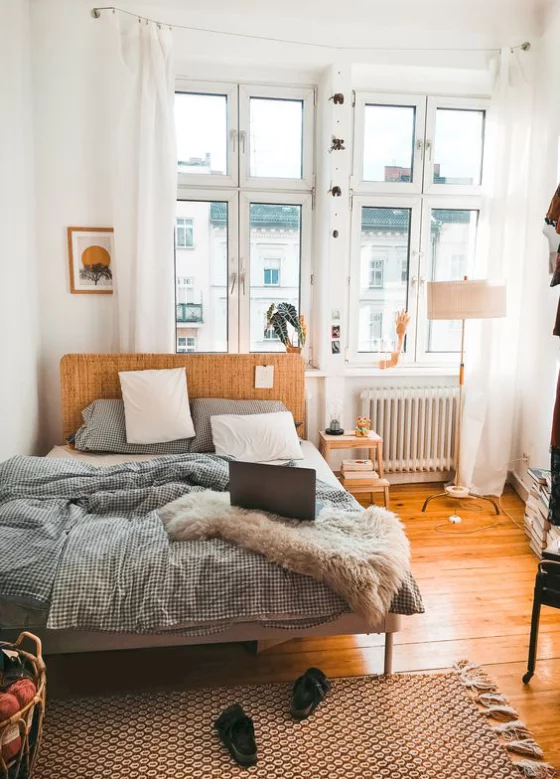 kleines Schlafzimmer Holzboden Bett aus Holz beige Bettdecke großes Fenster