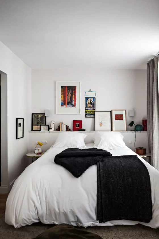 kleines Schlafzimmer einfaches Interieur Schlafbett weiße Bettwäsche Regal Akzente in Schwarz Kontrast