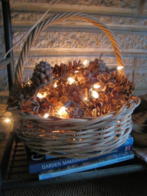 Herbstdeko mit Tannenzapfen in einem Korb auf dem Boden mit Lichterkette Bastelidee für Romantiker