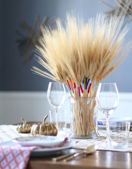 Herbstdeko mit Weizen Blickfang Glas mit Weizenstängeln dekoriert auf dem herbstlich geschmückten Esstisch zwei kleine Kürbisse