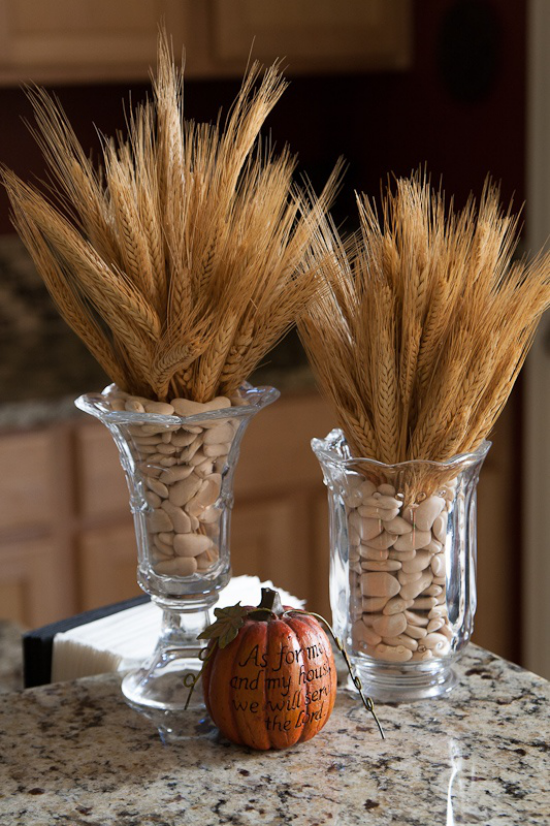  Φθινοπωρινή διακόσμηση με σιτάρι δύο ψηλά γυάλινα αγγεία γεμάτα με φασόλια σε αυτά Μίσχοι σιταριού Κολοκύθα τοποθετημένη στο τραπέζι 