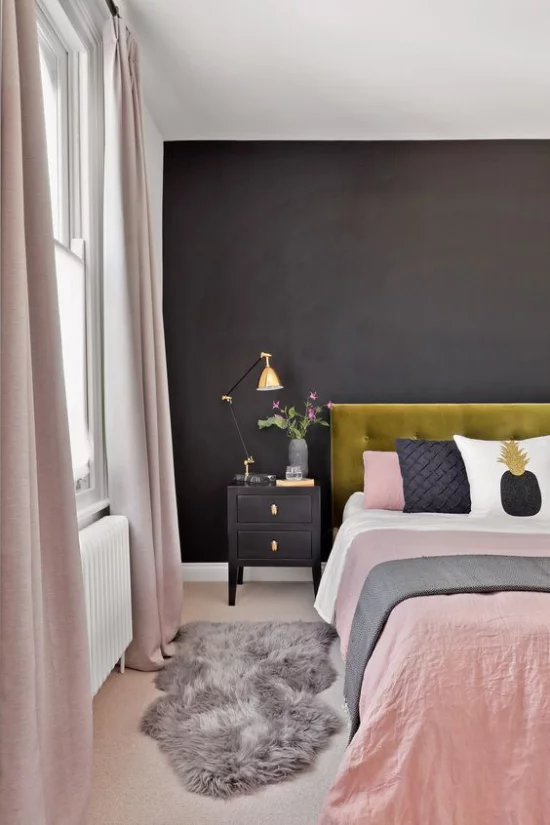 Schlafzimmer Ideen in Schwarz und Rosa helles Interieur schwarze Wand grasgrünes Bettkopfteil Bettwäsche rosa weiß grau kleiner Teppich aus Kunstpelz