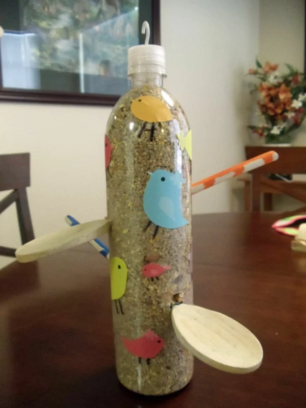 Plastikflasche mit Futter füllen Holzlöffel anbringen Vogelfutterspender selber bauen Kreativität zeigen 