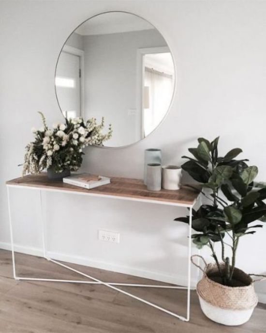 Eingangsbereich einfacher Konsolentisch runder Spiegel grüne Topfpflanze grüne Zweige in Vase modern und einladend gestalten
