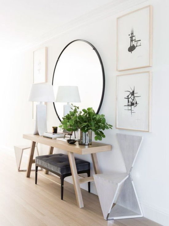 Eingangsbereich modern gestalten runder Spiegel weiße Tischlampe einfache Möbelstücke Wandbilder