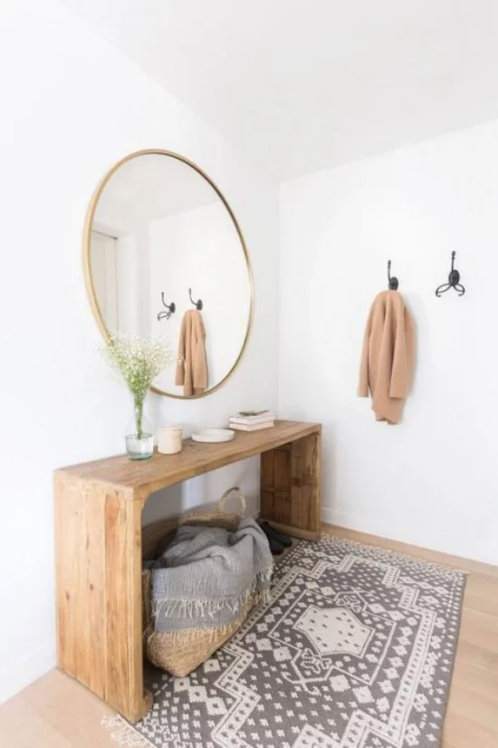 Eingangsbereich modern gestalten simpel einfache Einrichtung wenig Möbel runder Wandspiegel Holzboden Teppich