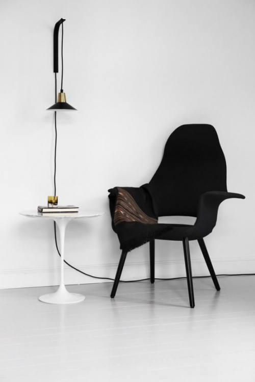 Extravagante Wandleuchten raffiniert auffallend in Industrial Style auf weißem rundem Tisch daneben schwarzer Sessel