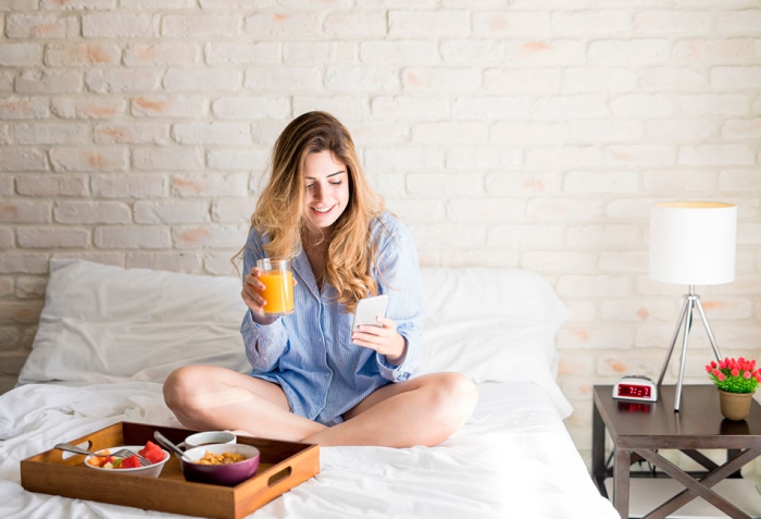 Sternzeichen gern alleine unabhängige Einzelgänger junges Mädchen im Bett sitzen Obst essen per Handy kommunizieren