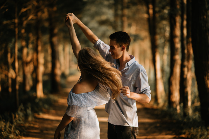 Verliebt sein glückliches junges Paar tanzt im Wald rosarote Brille aufsetzen