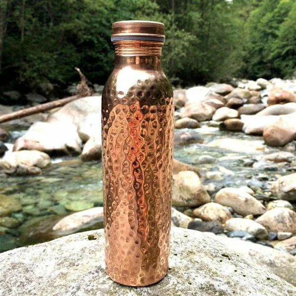 Kupferflasche auf dem Stein am Fluss 