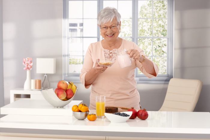Abnehmen im Alter Frau in der Küche den Tag beginnen mit leichtem Frühstück Saft viel Obst