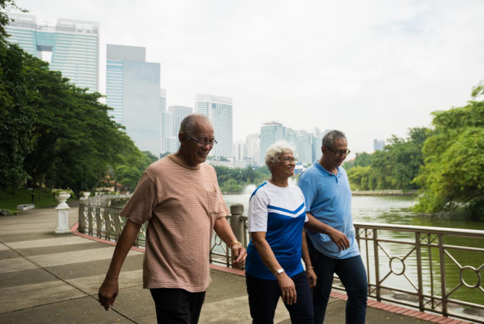 Abnehmen im Alter drei Freunde bei Spaziergehen am Fluss vorbei im Park in einer Großstadt