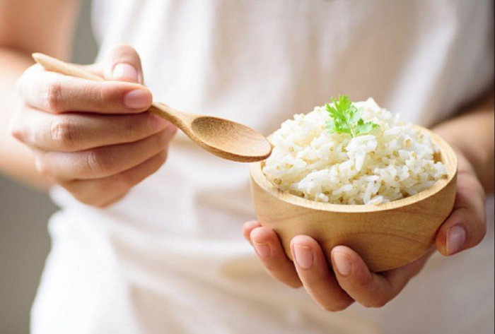Reisdiät ein einziges Lebensmittel gekochter Reis in einer kleinen Schale aus Holz Blätter Petersilie