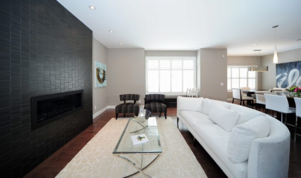 Schwarze Wand Blickfang geräumiges Wohnzimmer weiße Couch Teppich zwei Sessel Kaffeetisch aus Glas