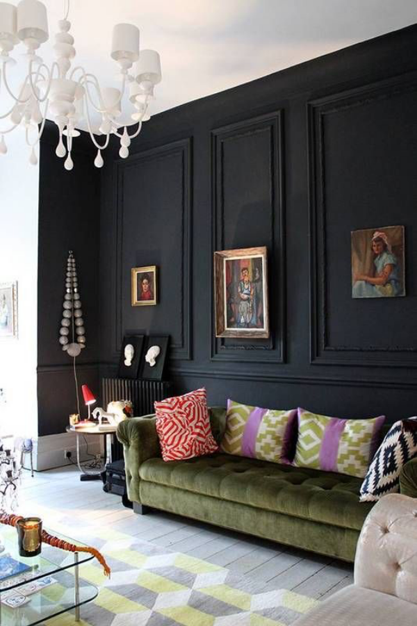 Schwarze Wand im Wohnzimmer viele Deko Artikel Bilder Kristallkronleuchter grüne Ledercouch bunte Kissen