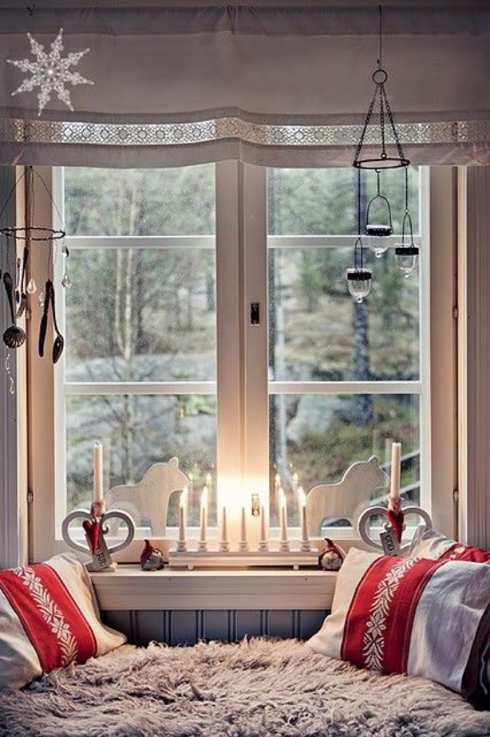 Weihnachtliche Fensterdeko weiße Holzfiguren Kerzen auf der Fensterbank Teelichter hängen