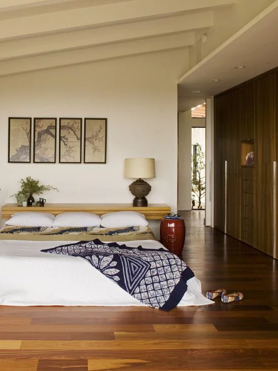 Zen Schlafzimmer weites komfortables Schlafbett Kissen visuelle Akzente gemusterte Decke in Dunkelblau und Grau hohe Vase in Karminrot neben dem Bett