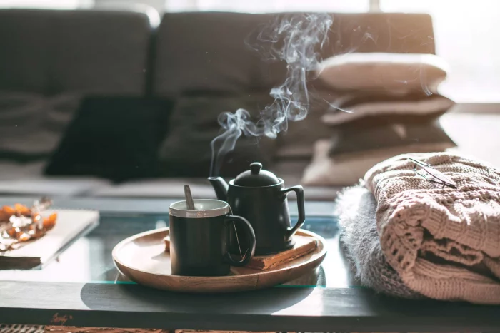gesund und glücklich im Winter bleiben aromatischer Tee duftet auf dem Kaffeetisch kuschelweiche Decken daneben