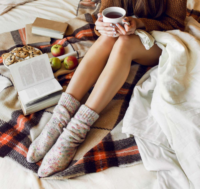 gesund und glücklich im Winter bleiben junge Frau im Bett kleine Süßigkeiten Äpfel heißer Tee angenehme gemütliche Atmosphäre