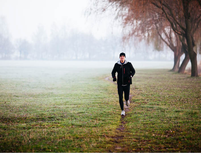 gesund und glücklich im Winter bleiben junger Mann joggen bei schlechtem Wetter fit sein