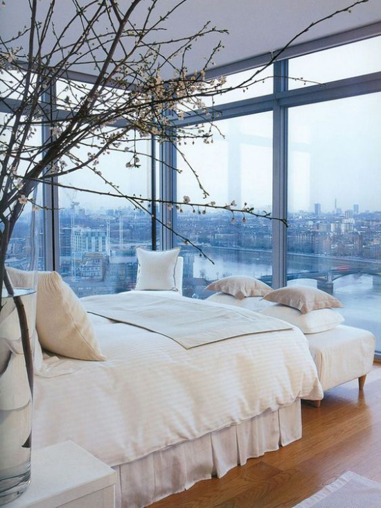 Glaswände im Schlafzimmer herrliche Aussicht Stadtpanorama Zweige in Vase neben dem Schlafbett